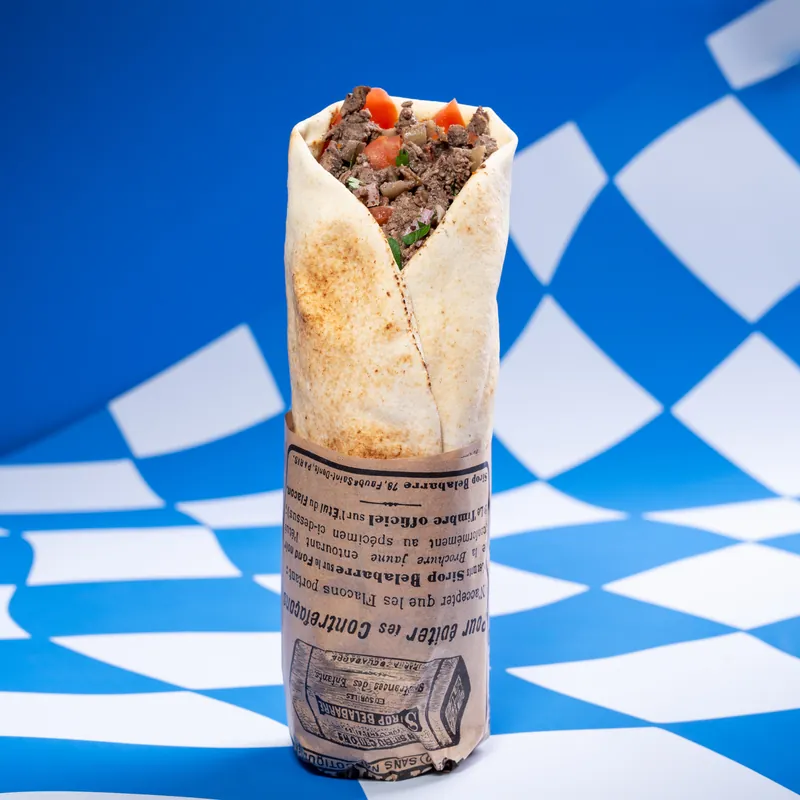 Pita shawarma bœuf Shawar'Mama dans son papier journal, sur le damier bleu
